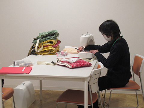 （写真）ミシンを使うボランティアさん
