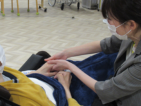 （写真）利用者さんにネイルやハンドトリートメントを行っている様子