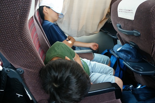 バスで寝る子どもの写真